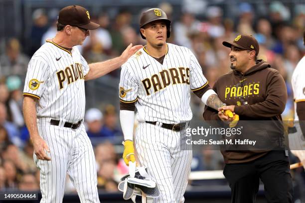 Manager Bob Melvin and trainer Ricky Huerta walk with Manny Machado of the San Diego Padres after he was hit by a pitch on the wrist during the...