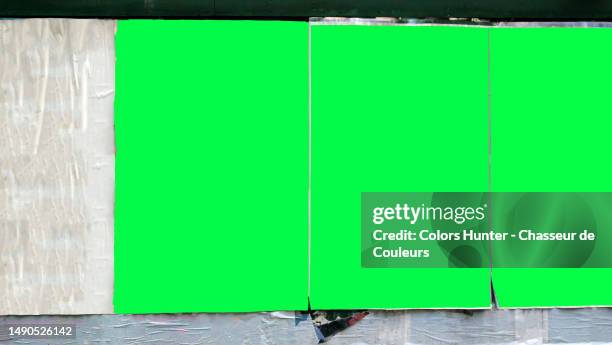 three green backgrounds with irregular contours on a wall covered by wrinkled and torn white posters in manhattan, new york city, united states - poster wall stock-fotos und bilder