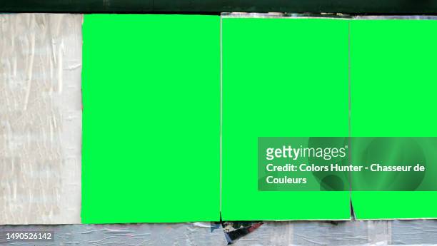 three green backgrounds with irregular contours on a wall covered by wrinkled and torn white posters in manhattan, new york city, united states - poster wall stockfoto's en -beelden