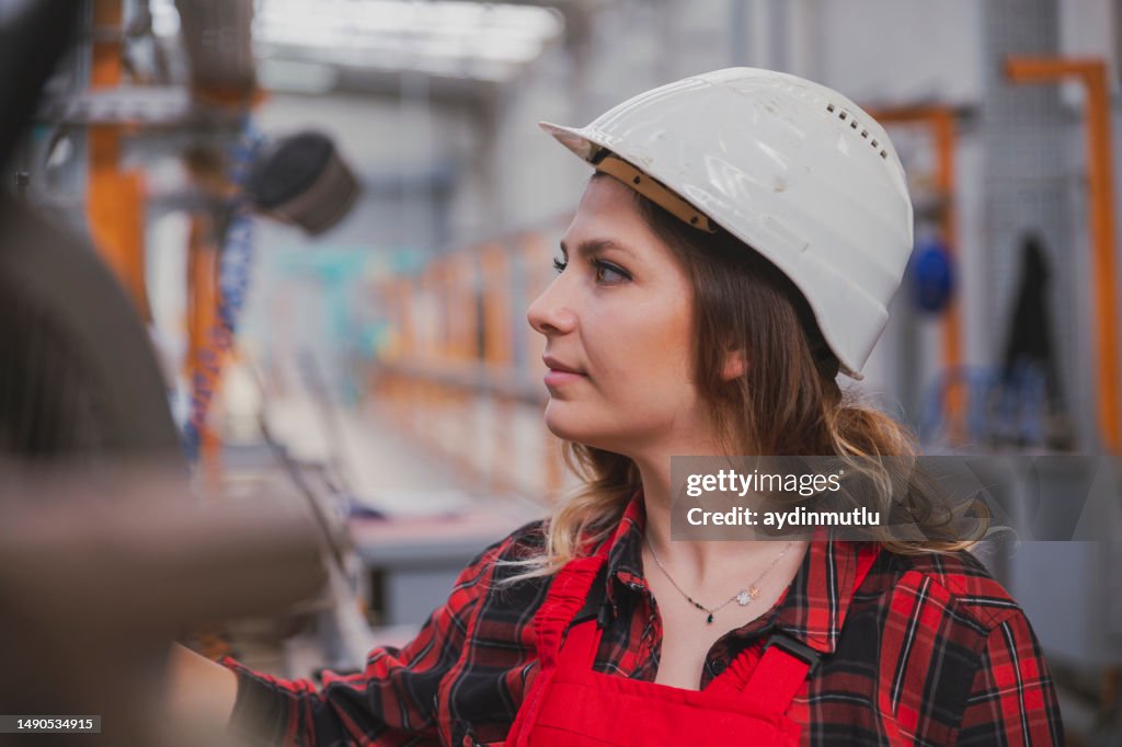 Mulher nova do coordenador do aprendiz que trabalha com a máquina do CNC na fábrica