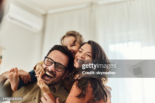 Fröhliches Mädchen, das Spaß mit ihren Eltern zu Hause hat. Fröhliches Mädchen, das Spaß mit ihren Eltern zu Hause hat.