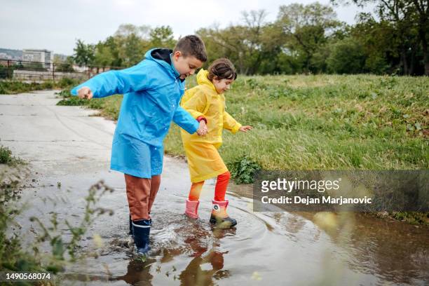 kids playing in water puddle on cloudy day - gå i land bildbanksfoton och bilder