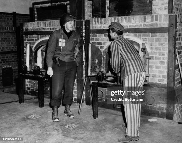 Former prisoner of Dachau concentration camp shows the crematory furnaces to Colonel Walter P O'Brien of the 157th Infantry Regiment whose troops had...