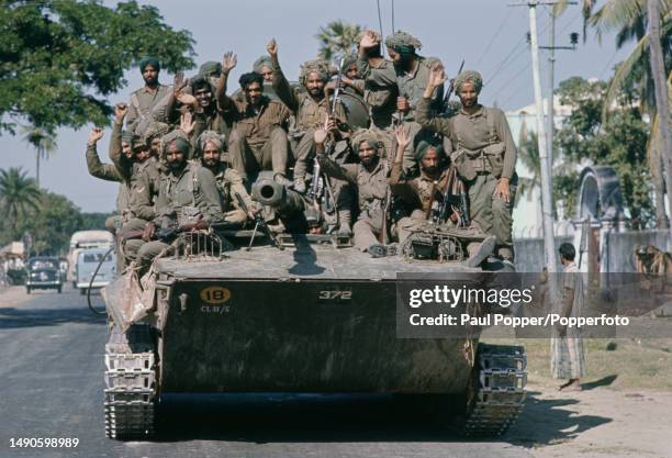 Sikh soldiers from the 45th Cavalry, Armoured Corps of the Indian Army, crowded onto a Soviet built PT-76 amphibious light tank, cheer and wave as...