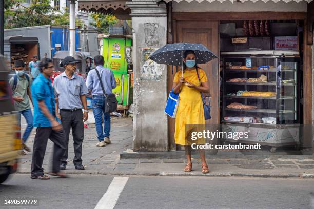 junge frau mit einer gesichtsmaske und einem regenschirm, um schatten für die sonne zu spenden - kandy kandy district sri lanka stock-fotos und bilder