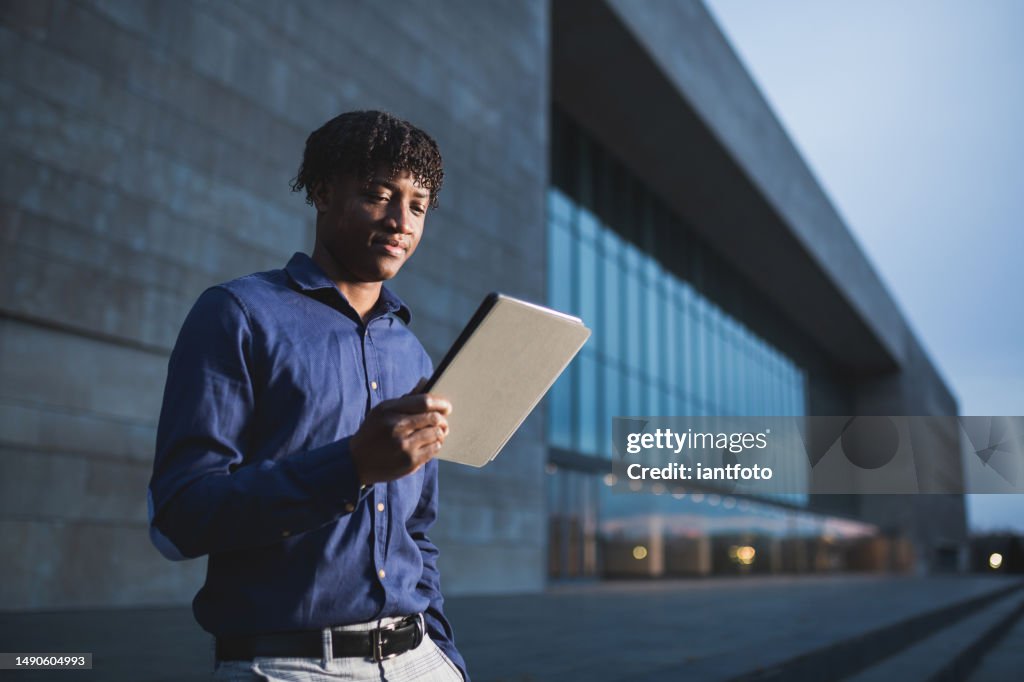 Homme d’affaires afro-américain dans le quartier financier avec sa tablette numérique.