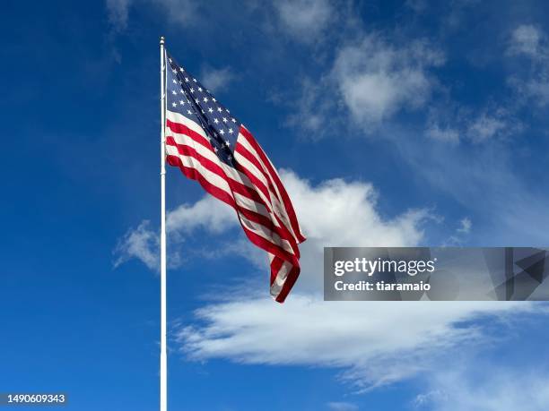 american flag blowing in the wind with a partly cloudy blue sky, usa - pole positie fotografías e imágenes de stock