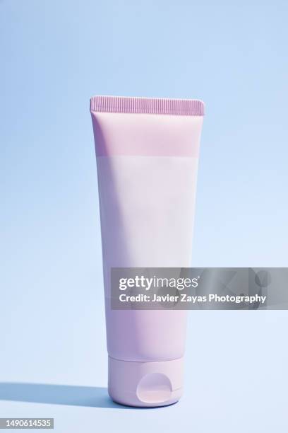 generic pink cream tube on blue background - creme tube ストックフォトと画像
