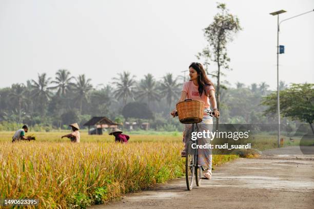 have fun by bike in the village with farmer harvesting rice on the background - yogyakarta stock pictures, royalty-free photos & images