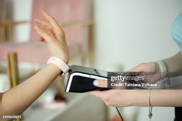 modern shopping: view of two people hands making contactless payment using smart watch - bracelet stock pictures, royalty-free photos & images