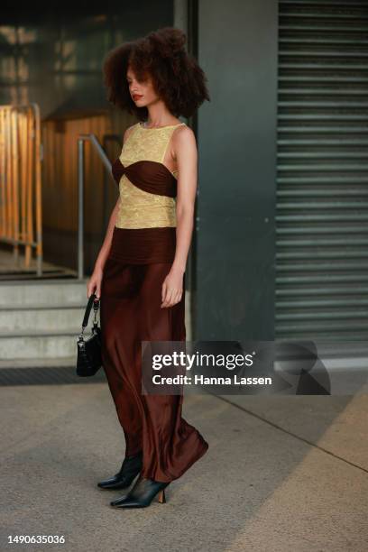 Guest wearing Bec and Bridge yellow lace top and brown silky skirt at Afterpay Australian Fashion Week 2023 at Carriageworks on May 16, 2023 in...
