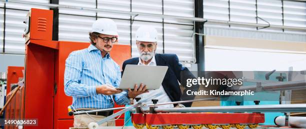 mature adult, senior caucasian male engineer or entrepreneur manager discuss talk using laptop computer, work together in factory. logistic industry business, industrial job, or people at work concept - team talk stockfoto's en -beelden