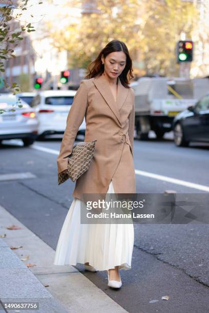 Cai wearing white Dion Lee dress, Anna Quan beige jacket and Corto clutch at Afterpay Australian Fashion Week 2023 at Carriageworks on May 16, 2023...