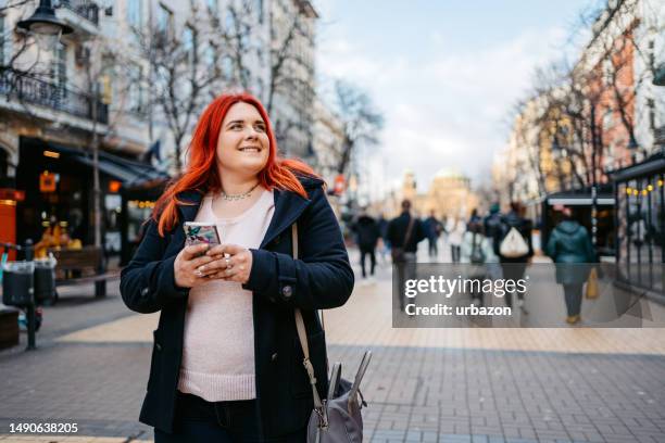 mujer joven usando el teléfono en la plaza de la ciudad en sofía - fat redhead fotografías e imágenes de stock