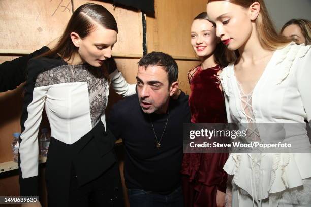 Backstage at the Antonio Berardi show during London Fashion Week Autumn/Winter 2016/17, the designer is with three models wearing garments from his...