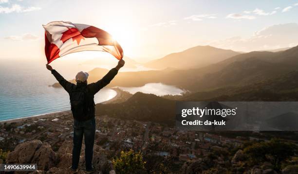 a celebration of national pride. man holds waving national flag of canada standing at the top at sunset. beautiful mountains and sea on background. - canadians celebrate national day of independence stock pictures, royalty-free photos & images