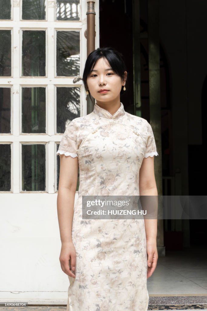 Beautiful Chinese woman in cheongsam standing next to a traditional building