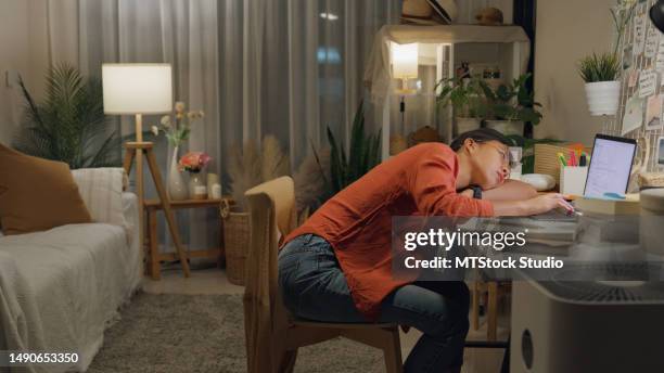 joven mujer asiática usa asiento casual frente al escritorio con computadora portátil sintiéndose infeliz estresada por el problema de la deuda en la idea de trabajo en la sala de estar de la casa por la noche. trabaja desde casa. - perder el tiempo fotografías e imágenes de stock