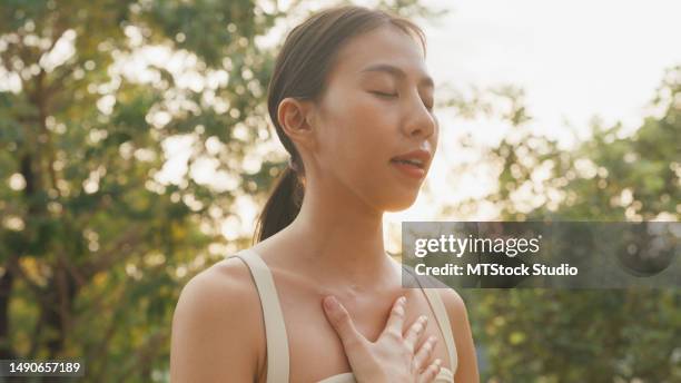 young asian women healthy lifestyle practice yoga outdoors standing in city park. healthy lifestyle and exercises. - hands on chest stock pictures, royalty-free photos & images