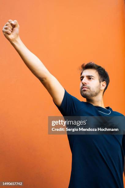 latino man raising his hand and fist for unity, empowerment, determination, solidarity - punching the air stock pictures, royalty-free photos & images