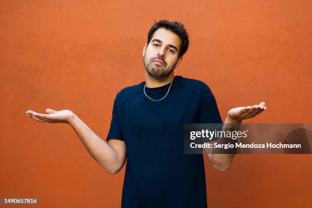 latino man shrugging his shoulders with hands spread out - shrug shoulders stockfoto's en -beelden