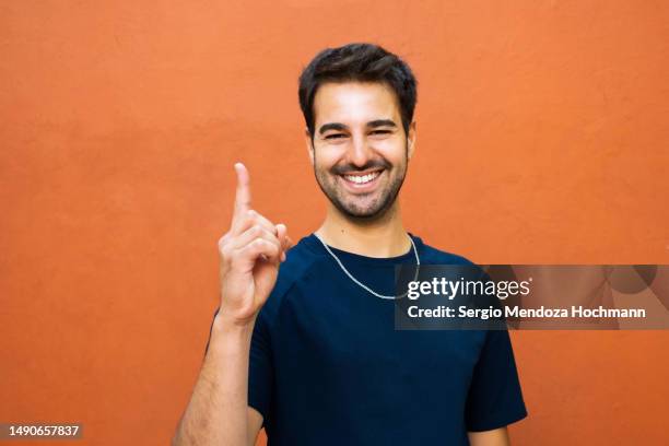 latino man looking at the camera and giving the number one sign - guy with attitude mid shot stock-fotos und bilder