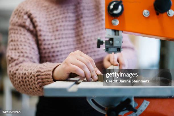 filigree hands sawing a piece of wood on a sawing machine - stichsäge stock-fotos und bilder