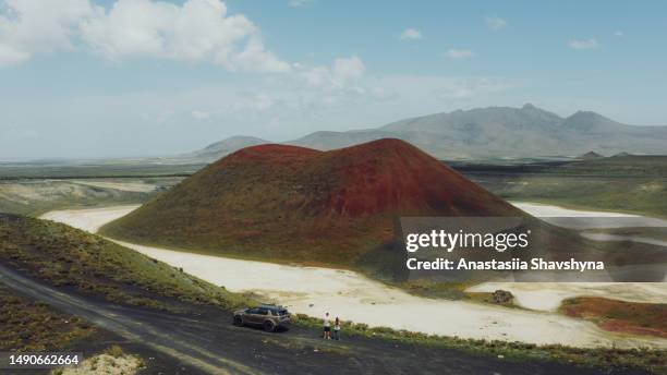 aerial view of woman and man with a car on top of hill looking at the red volcano crater - stratovolcano 個照片及圖片檔