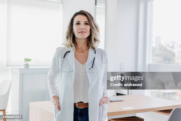 portrait d’une femme médecin regardant la caméra dans le bureau du médecin - pratique-médicale photos et images de collection