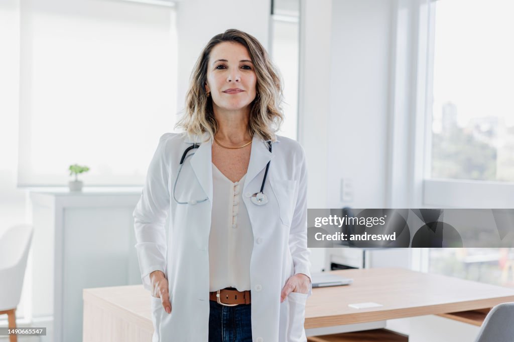 Ritratto di medico femminile che guarda la macchina fotografica nello studio del medico