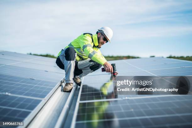 arbeiter mit bohrer zur befestigung von sonnenkollektoren. - solar farm stock-fotos und bilder