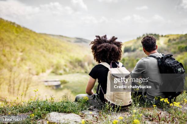 father and son with backpacks enjoys view in the mountains - family from behind stock pictures, royalty-free photos & images