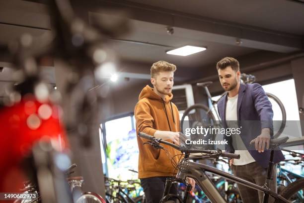 verkäufer und männlicher kunde im fahrradgeschäft - sportgeschäft stock-fotos und bilder