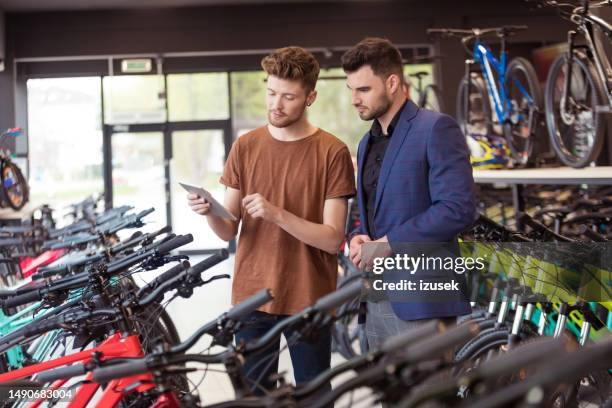 salesman and male customer in bicycle shop - bike store stock pictures, royalty-free photos & images