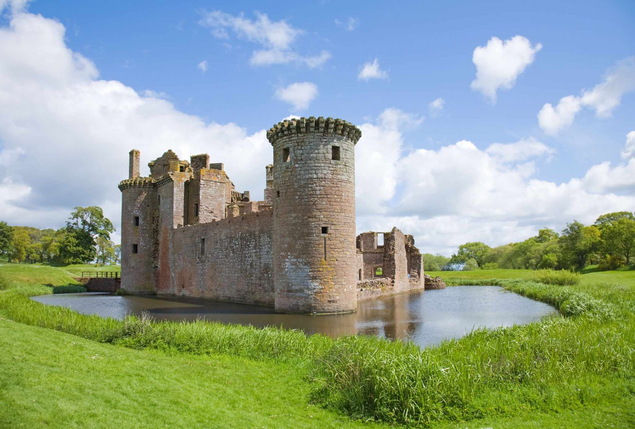 Castle surrounded by moat and green grass field Castle surrounded by moat and green grass field