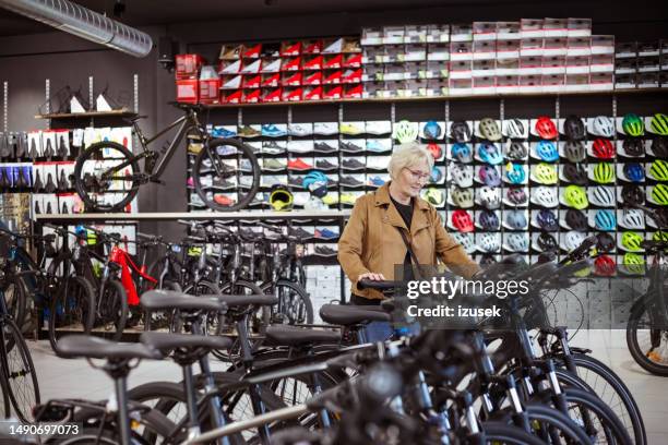 senior woman in bicycle shop - elcykel bildbanksfoton och bilder