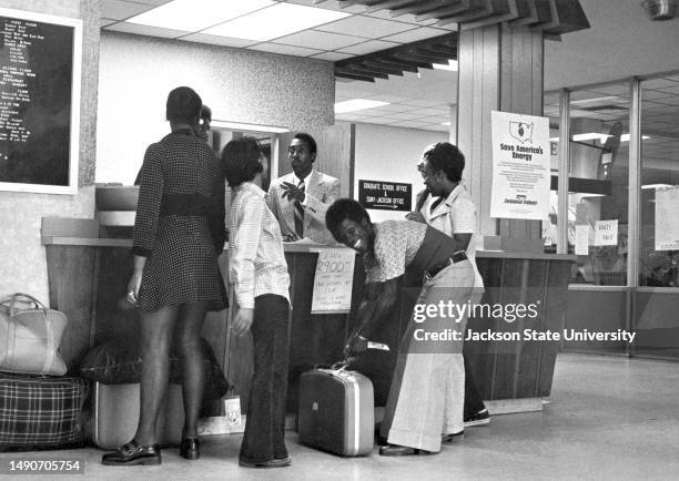 University students talking with staff at reception desk.