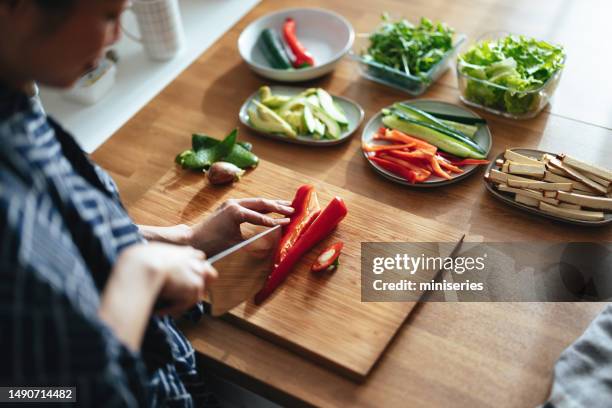 unrecognizable woman cutting a paprika on a kitchen board - paprika stock pictures, royalty-free photos & images