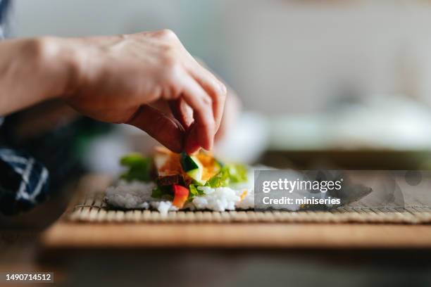 nahaufnahme einer anonymen frau, die vegetarische sushi-rollen macht - sushi stock-fotos und bilder