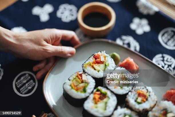 unrecognizable woman holding a plate with sushi rolls - making sushi stock pictures, royalty-free photos & images