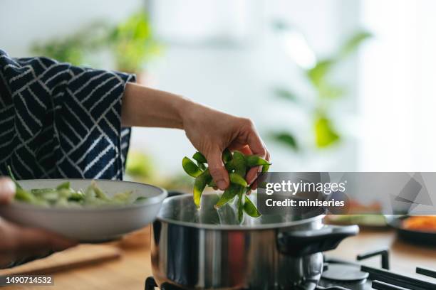 anonymous woman adding edamame to a cooking pot - crisp stock pictures, royalty-free photos & images