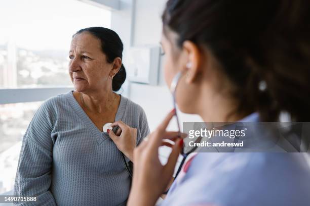 krankenschwester hört den herzschlag des patienten durch stethoskop ab - stethoscope heart stock-fotos und bilder