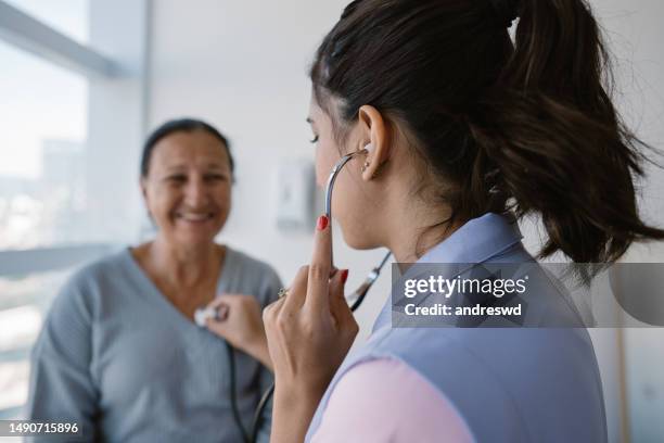 nurse listening to patient's heartbeat through stethoscope - listening to heartbeat 個照片及圖片檔