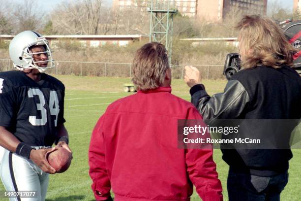 Award-winning professional baseball and football player Bo Jackson listens to direction wearing his Los Angeles Raiders uniform and carrying a...