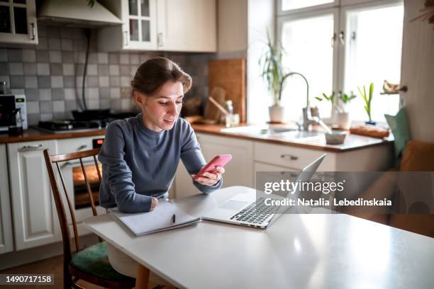 disabled shopping made easy: middle-aged woman with amputated arm uses technology to shop online at home - laptop smartphone stock pictures, royalty-free photos & images