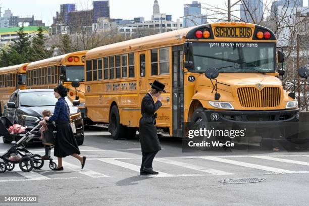 eine jüdisch-chassidische familie überquert eine straße in brooklyn. mehrere gelbe schulbusse im hintergrund. - hasidic jews stock-fotos und bilder