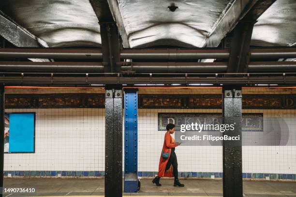 eine frau geht in der dekalb ave station in brooklyn spazieren - fußgängertunnel stock-fotos und bilder