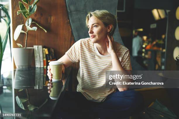 portrait of beautiful a 35-year-old woman with short blonde hair sitting at workstation in design firm - portrait of cool creative businesswoman at office stock-fotos und bilder