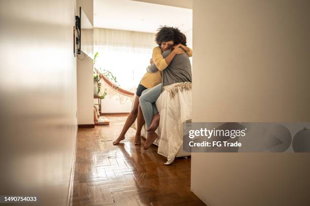 mulher nova abraçando sua namorada sentada na cama no quarto em casa - fazer as pazes - fotografias e filmes do acervo