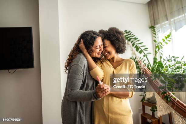 pareja de lesbianas realizando una prueba de embarazo en casa - prueba-de-embarazo fotografías e imágenes de stock